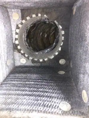 Interior view of a dust-filled air duct or ventilation shaft, with a circular metal vent or fan in the center and dust accumulation—highlighting the need for professional air duct services New Jersey to ensure clean, healthy airflow.