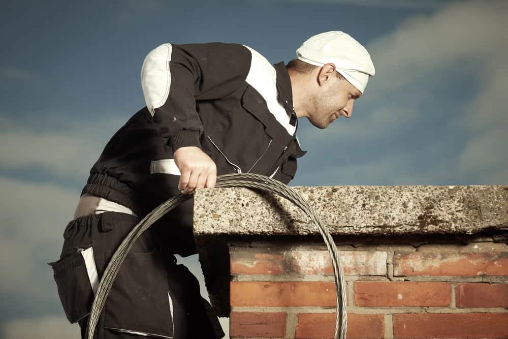 Chimney Sweep Man In Work Uniform Cleaning Chimney On Building