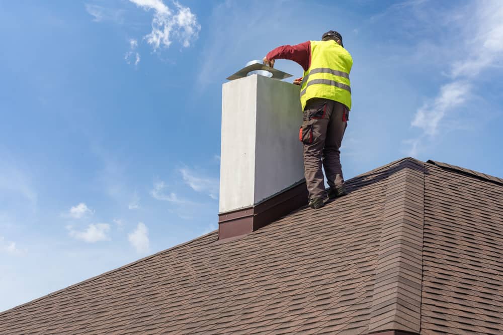 technician working on a chimney on a roof.