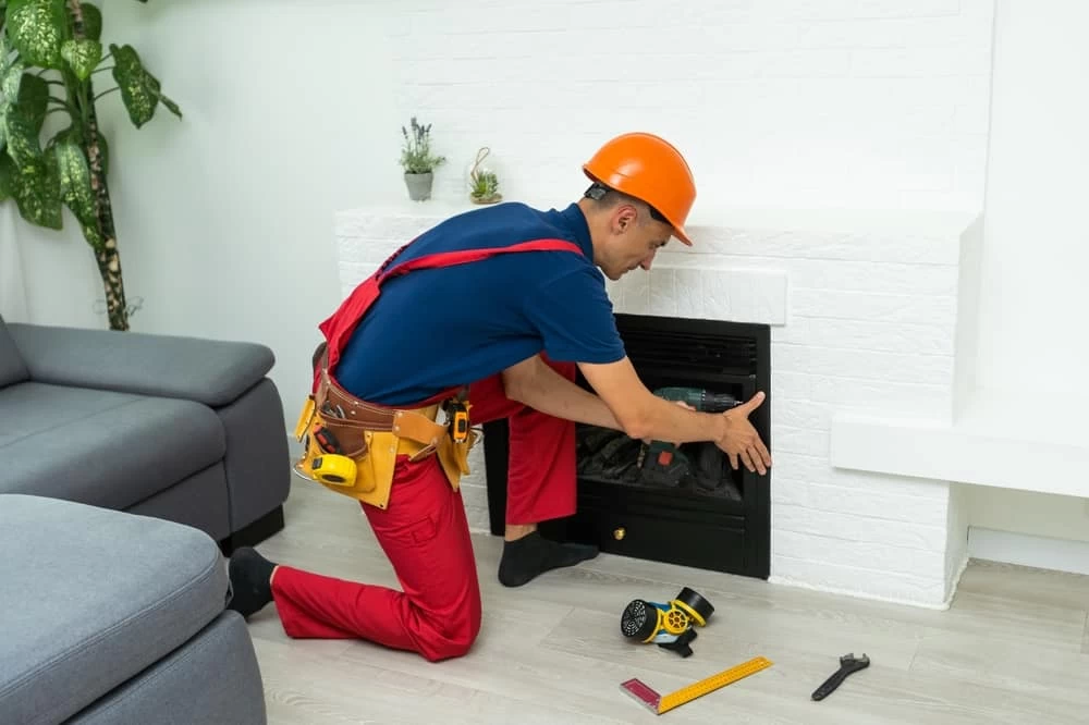A man in overalls and safety vest fixing a fireplace.