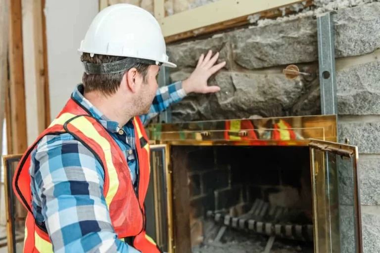 A man in a hard hat and safety vest is fixing a fireplace.