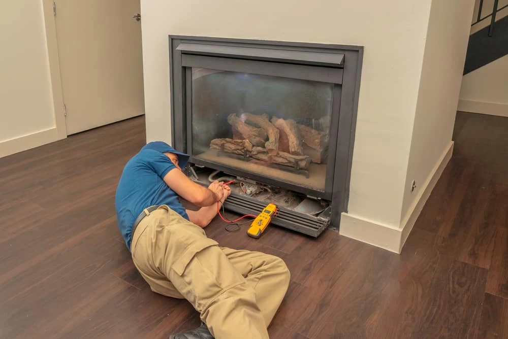 A man laying on the floor next to a fireplace.