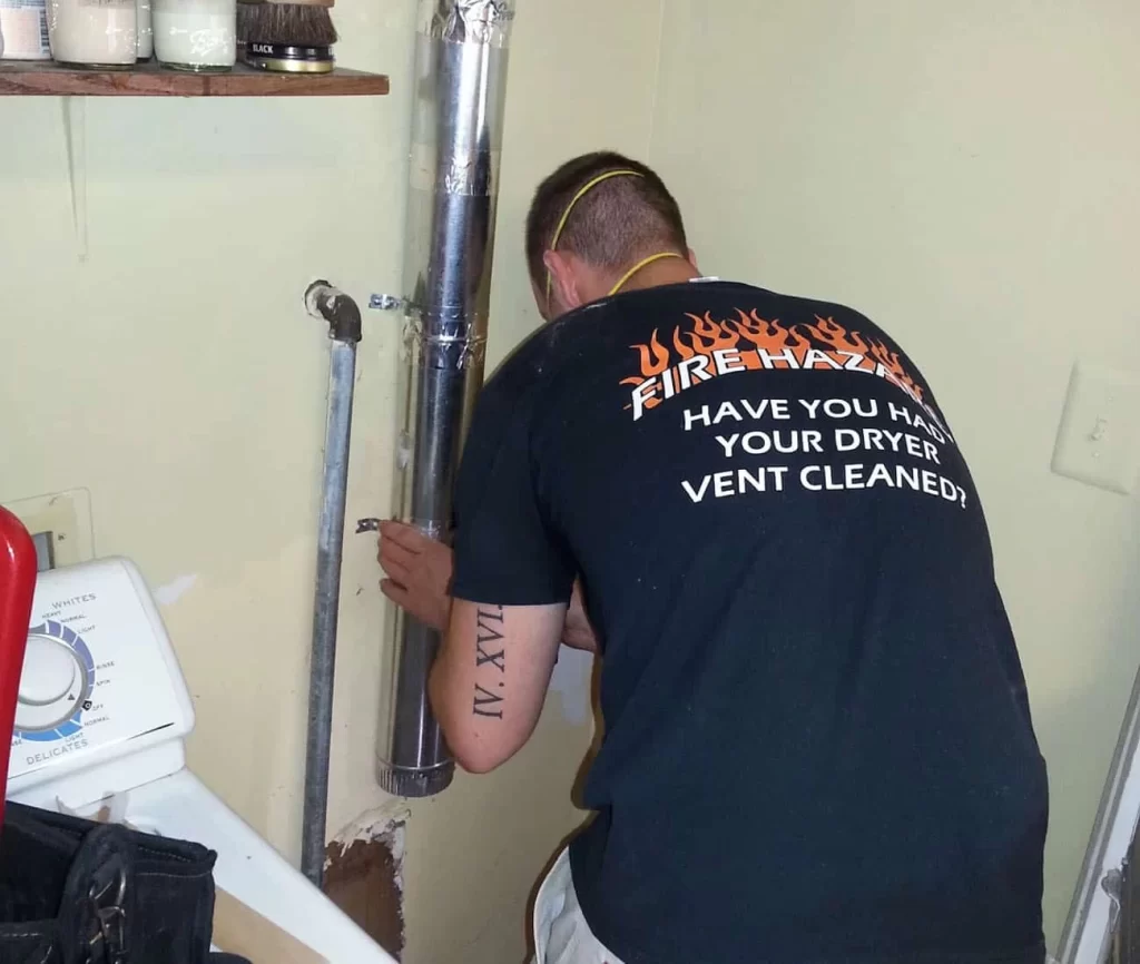A man in a black shirt is fixing a pipe.