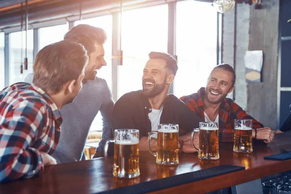 Happy Young Men in Casual Clothing Drinking Beer and Laughing