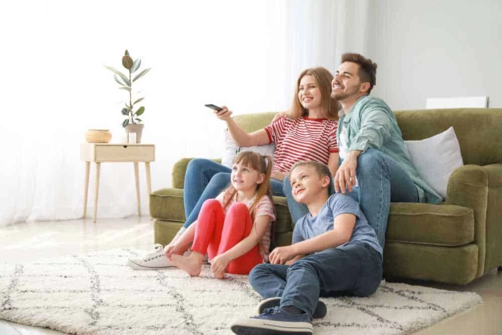 A family sitting on a couch watching tv.