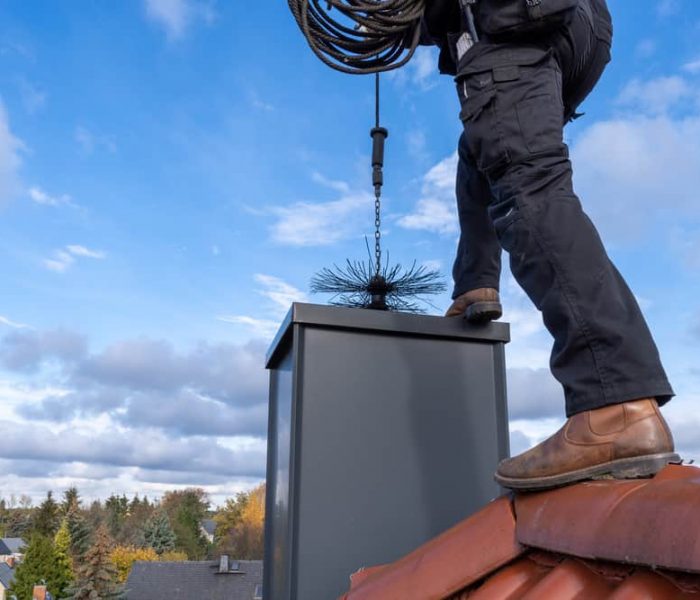 Chimney,Sweep,Cleaning,A,Chimney,Standing,On,The,House,Roof,